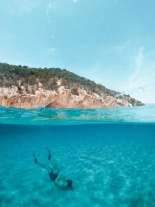 Person snorkeling near a rocky shore.