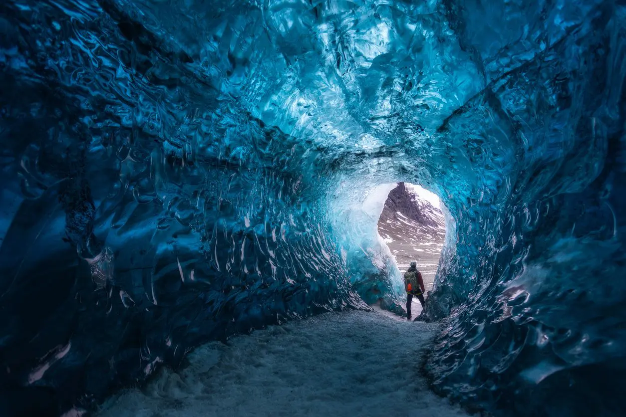 Person exploring a stunning blue ice cave.